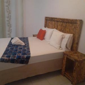 a bedroom with a bed with a wooden headboard and pillows at Sunshinevibe guest house in Kasane