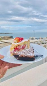 una persona sosteniendo un plato con un pedazo de pastel en FONTEblu B&B, en Polignano a Mare