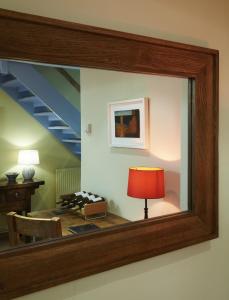 a mirror on a wall with a table and a red lamp at Hang Your Hat in Winchester