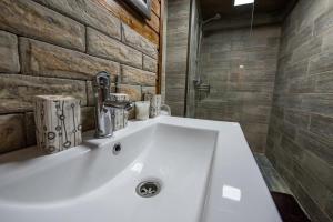 a white sink in a bathroom with a stone wall at Evdo Apartments Loft2 Wooden House in Gudauri