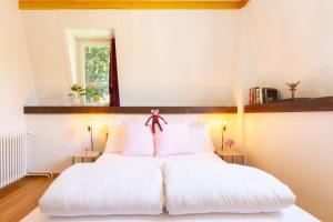 una camera da letto con un letto bianco e cuscini rosa di Hotel Beau Séjour Lucerne a Lucerna