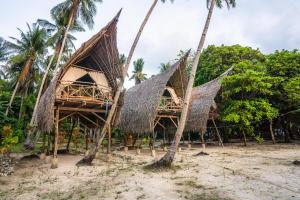 two bamboo huts on the beach with palm trees at Isla - The Island Experience in El Nido