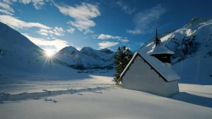 kościół w śniegu z górami w tle w obiekcie AlpenGold Hotel Davos w Davos