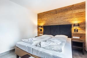 ein Schlafzimmer mit einem großen Bett und einer Holzwand in der Unterkunft Mountain Lodge Leogang - Top4 in Leogang