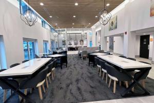 a dining room with tables and chairs and chandeliers at La Quinta by Wyndham Chicago O'Hare Airport in Rosemont