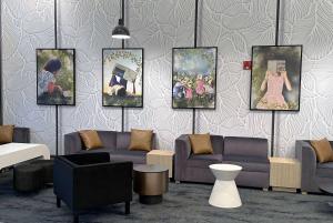 a living room with couches and paintings on a wall at La Quinta by Wyndham Chicago O'Hare Airport in Rosemont