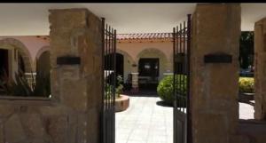 una entrada a un patio con una puerta de hierro forjado en Mirasoles Hotel, en Mina Clavero