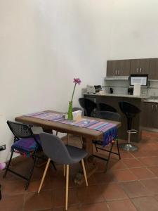 une table avec des chaises et un vase avec une fleur dans l'établissement El Calvario Lofts, à Antigua Guatemala