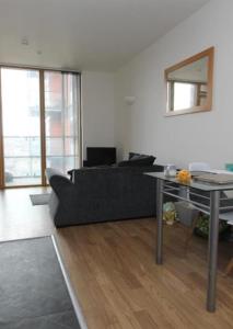 a living room with a black couch and a table at Arena Apartment in Manchester