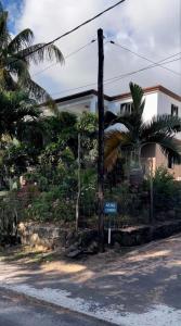 a street sign in front of a house with palm trees at Résidence au bout du Morne in Le Morne