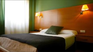 a bedroom with a bed with a wooden head board at Hotel San Millán in Santander