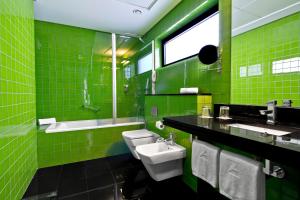 Baño verde con 2 aseos y lavamanos en SANA Capitol Hotel, en Lisboa