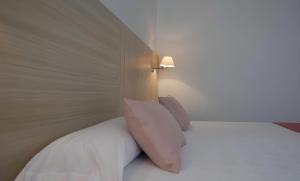 a bed with white pillows and a light on the wall at Hotel San Millán in Santander