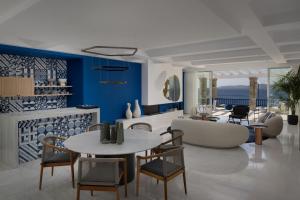 - un salon avec des murs bleus, une table et des chaises dans l'établissement Mykonos Grand Hotel & Resort, à Agios Ioannis Mykonos