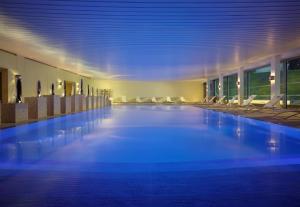 a large swimming pool in a building with chairs at Coworth Park - Dorchester Collection in Ascot