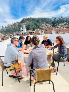 un grupo de personas sentadas en mesas en un techo en Montañero Hostel en Huaraz