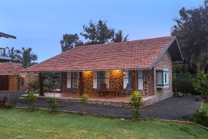 uma casa de tijolos com um pátio no quintal em SaffronStays Lake House Marigold, Nashik - rustic cottages with private plunge pool em Nashik