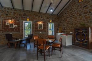 uma sala de jantar com mesas e cadeiras numa parede de tijolos em SaffronStays Lake House Marigold, Nashik - rustic cottages with private plunge pool em Nashik