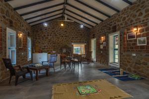 um quarto com uma mesa e cadeiras numa parede de tijolos em SaffronStays Lake House Marigold, Nashik - rustic cottages with private plunge pool em Nashik