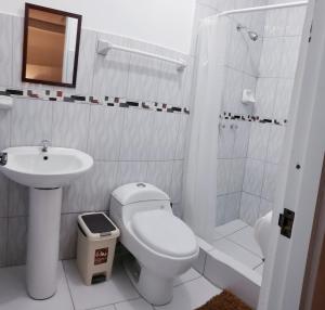 Baño blanco con aseo y lavamanos en Hostal Cusco de mis Sueños, en Cusco