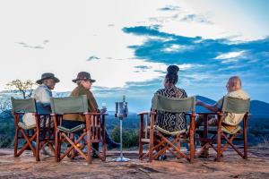 un grupo de personas sentadas en sillas en una mesa en Kilaguni Serena Safari Lodge, en Tsavo