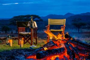 dos sillas sentadas junto a un fuego y dos sillas en Kilaguni Serena Safari Lodge, en Tsavo