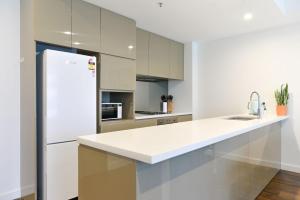 cocina con armarios blancos y nevera blanca en Sydney CBD Modern 2 bedroom Apartment, en Sídney