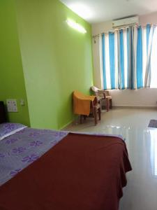 a bedroom with a bed and a chair and windows at Relax inn in Matheran