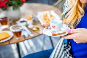 a woman holding a cup of coffee and a plate of food at Velinov Boutique Hotel in Bansko