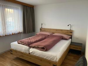 a bedroom with a wooden bed with two pillows at Haus Castello in Saas-Almagell