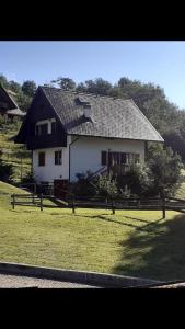 a white house with a black roof in a field at Casa vacanze Ravascletto in Ravascletto