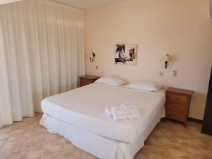 ein Schlafzimmer mit einem weißen Bett mit zwei Handtüchern darauf in der Unterkunft Hotel Aquarella in Punta Del Diablo