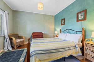 1 dormitorio con 1 cama y 1 silla en 15 Clarke Street Narooma, en Narooma