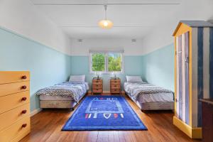 1 dormitorio con 2 camas y pared azul en 15 Clarke Street Narooma, en Narooma