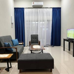 a living room with a couch and a tv and blue curtains at Homestay Ayer Keroh Tasik Utama in Ayer Keroh