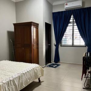 a bedroom with a bed and a dresser and a window at Homestay Ayer Keroh Tasik Utama in Ayer Keroh