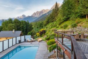 ein Haus mit einem Pool mit Bergen im Hintergrund in der Unterkunft Chalet Galadhrim Chamonix Mont Blanc Valley in Les Houches