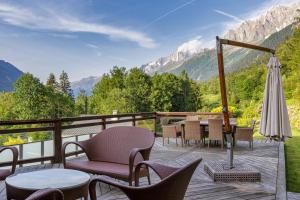 eine Terrasse mit Stühlen, einem Sonnenschirm und Bergen in der Unterkunft Chalet Galadhrim Chamonix Mont Blanc Valley in Les Houches