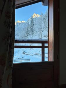 ein Fenster mit Blick auf einen verschneiten Berg in der Unterkunft Chalet Galadhrim Chamonix Mont Blanc Valley in Les Houches