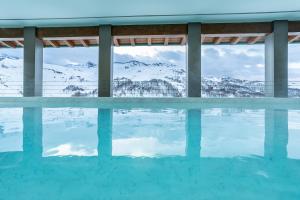 uma piscina com vista para as montanhas cobertas de neve em White Angel Hotel em Breuil-Cervinia