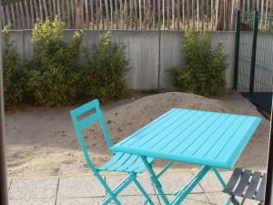 une chaise bleue assise dans le sable à côté d'une clôture dans l'établissement Charmante maisonnette à Quend Plage, 2 chambres, jardinet, parking, proche commodités - FR-1-482-45, à Quend