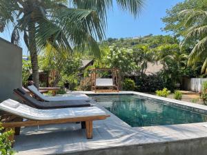 - une piscine avec 2 chaises longues et une table dans l'établissement maison vanilianadia, à Nosy Be