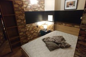 een kleine slaapkamer met een wit bed en een stenen muur bij Boutique & artistic 3 bedroom apartment. in Pamporovo