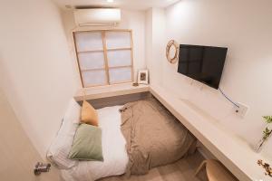 ein kleines Zimmer mit einem Sofa und einem Flachbild-TV in der Unterkunft ビジネスホテル韓国館 in Tokio