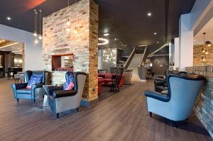 ein Wartezimmer mit blauen Stühlen und einer Ziegelwand in der Unterkunft Sandman Signature London Gatwick Hotel in Crawley