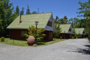 uma casa com um telhado verde ao lado de uma estrada em Cabañas Parque Salto del Laja em El Manzano