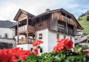 un edificio con balcón y flores rojas en Ciasa Somuer - Sorà, en San Vigilio Di Marebbe