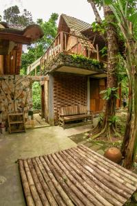 eine Veranda eines Hauses mit einer Bank und einem Baum in der Unterkunft Villa Kampung Ayem Riverside in Sleman