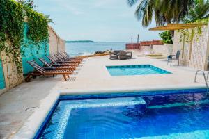 a swimming pool with chairs and the ocean in the background at Hotel Caribbean Cartagena in Cartagena de Indias