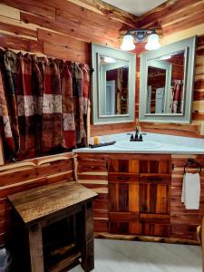 un bagno con lavandino, 2 specchi e una panca di Log Cabin Inn a Eureka Springs